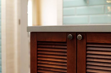 Ahşap mobilyaları ve naneli duvarları olan modern banyo detayları.