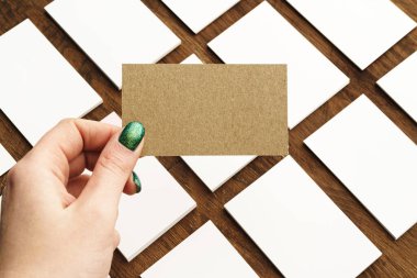 Kadın eli çalışma masasının üstünde iş kartı veriyor.