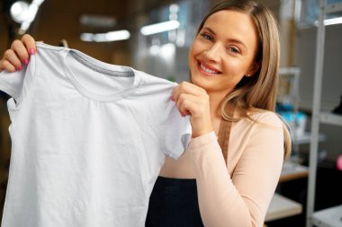 Terzi elinde tişört tutan hoş bir kadın.