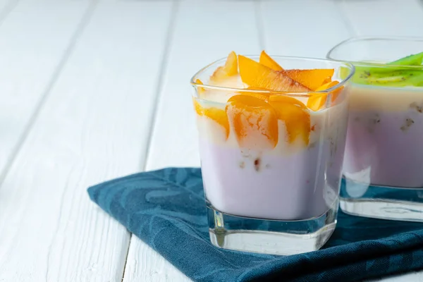 Copo de vidro com youghurt e fatias de frutas — Fotografia de Stock