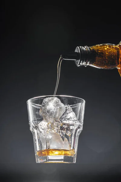 Whisky versando in un bicchiere su sfondo nero — Foto Stock