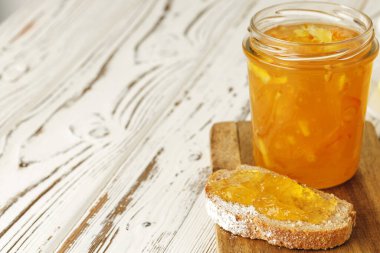 Tahtada meyve reçeli ile kaplı bir dilim ekmek.