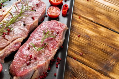 Koyu ahşap masada iki çiğ biftek.