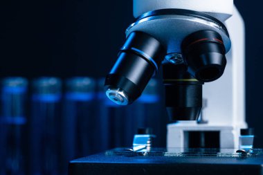 Laboratuvar mikroskobunu mavi sıvı test tüpleriyle kapatın.