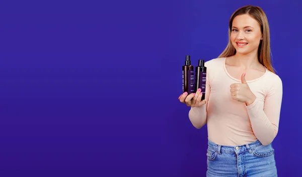 Приваблива молода біла жінка, що представляє пляшки косметичних продуктів — стокове фото