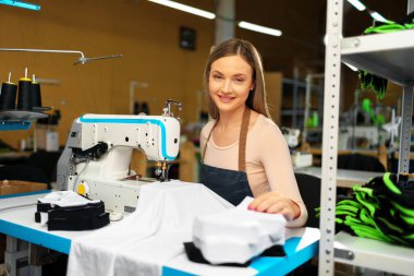 Güzel kadın terzi işyerinde kumaşla çalışıyor.