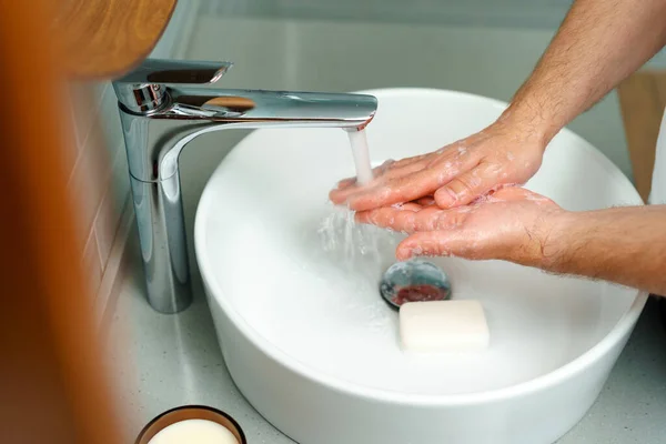 Закрыть фотографию мужских рук, моющихся с мылом над раковиной — стоковое фото