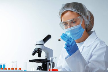 Laboratuvarda üzerinde kan örneği olan test tüpüne bakan kadın bilim adamı.