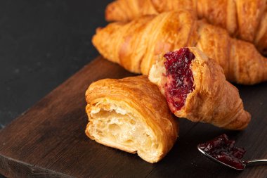 Koyu ahşap tahtada böğürtlen reçelli taze kruvasan.