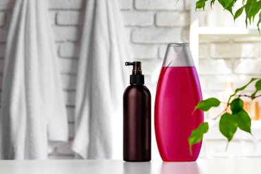 Beyaz banyo duvarına dayanan kozmetik şişeler