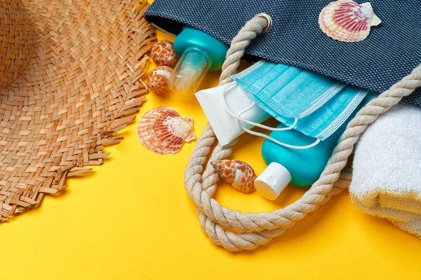 Bolso de playa azul con accesorios de playa y máscara protectora sobre fondo amarillo — Foto de Stock