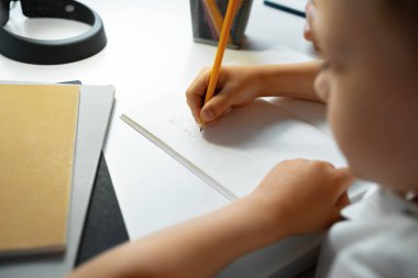 Küçük çocuk defterine bir şeyler yazıyor.