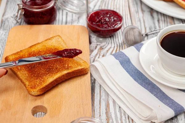 Фото кухонного стола с тостами, фруктовыми джемами и ножом — стоковое фото