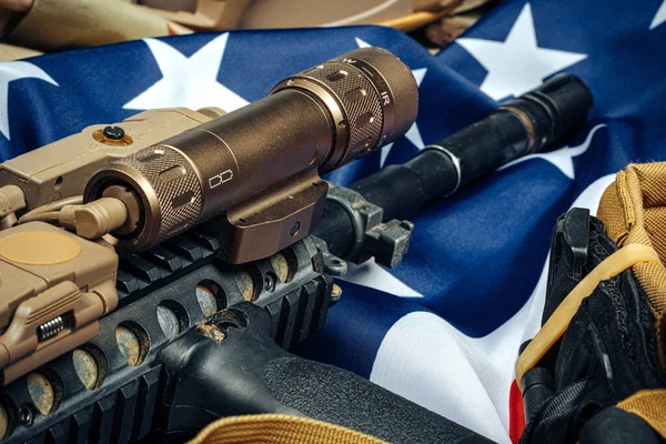 木製のテーブルにアメリカの戦闘旗とアサルトライフル. — ストック写真