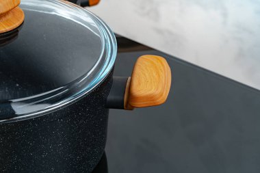 Gri duvara karşı indüksiyon sobasında siyah yemek takımı