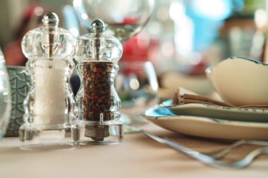 Yeşil şık bulaşık takımı ve gümüş çatal bıçak takımı olan zarif bir masa.