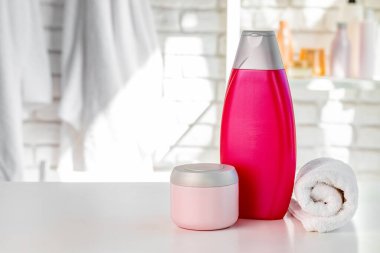 Beyaz banyo duvarına dayanan kozmetik şişeler