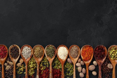 Siyah arka planda çeşitli baharatlı ahşap kaşıklar.