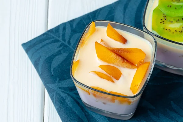 Copo de vidro com youghurt e fatias de frutas — Fotografia de Stock