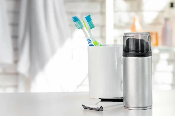Copo branco com escovas de dentes e toalhas no banheiro — Fotografia de Stock
