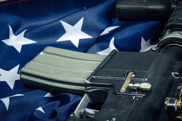 Bandera de batalla estadounidense y rifle de asalto en la mesa de madera . — Foto de Stock