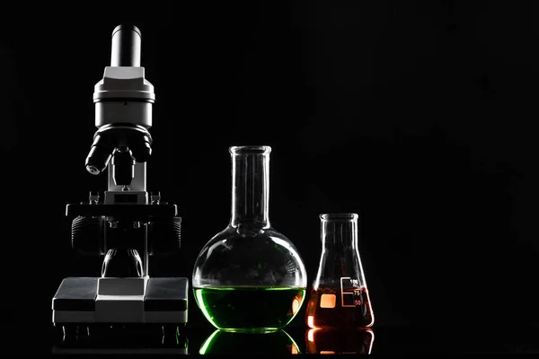 Microscópio de laboratório na mesa no escuro — Fotografia de Stock