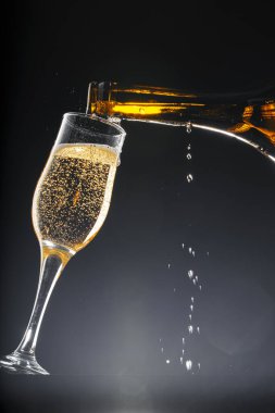Şampanya siyah arka planda cama dökülüyor.