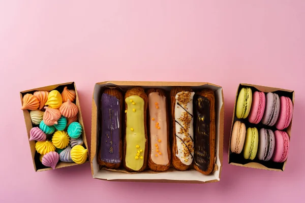 Cutii de carton cu prăjituri eclair și prăjituri pe suprafață roz — Fotografie, imagine de stoc