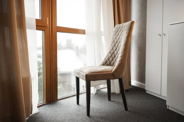 Silla marrón de pie cerca de una gran ventana en la habitación — Foto de Stock