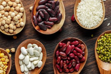 Tahta kaşıklar, tahıllar ve fasulyeler ahşap masada.