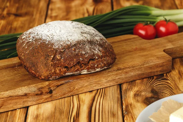Roggebrood op snijplank op houten tafel — Stockfoto