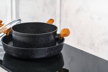 Gri duvara karşı indüksiyon sobasında siyah yemek takımı