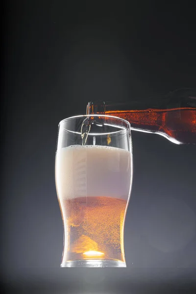 Пиво наливается в стекло на черном фоне — стоковое фото