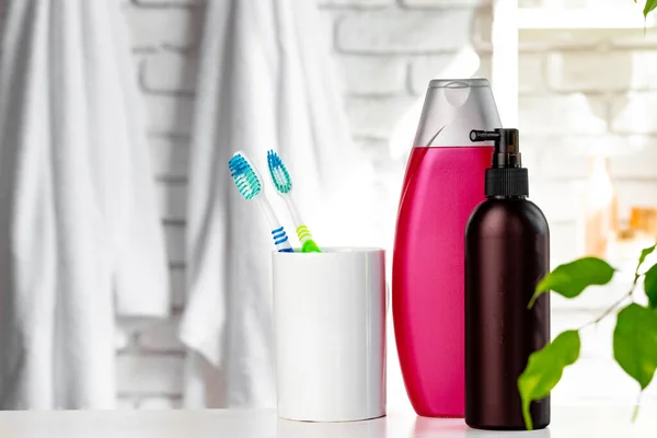 White cup with toothbrushes and towels in bathroom — Stock Photo, Image
