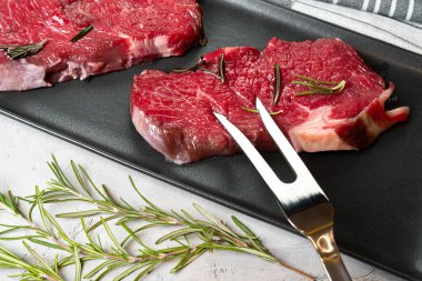 Siyah seramik tabakta iki taze çiğ biftek.