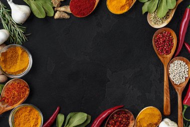 Siyah arka planda çeşitli baharatlı ahşap kaşıklar.