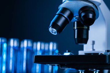 Laboratuvar mikroskobunu mavi sıvı test tüpleriyle kapatın.
