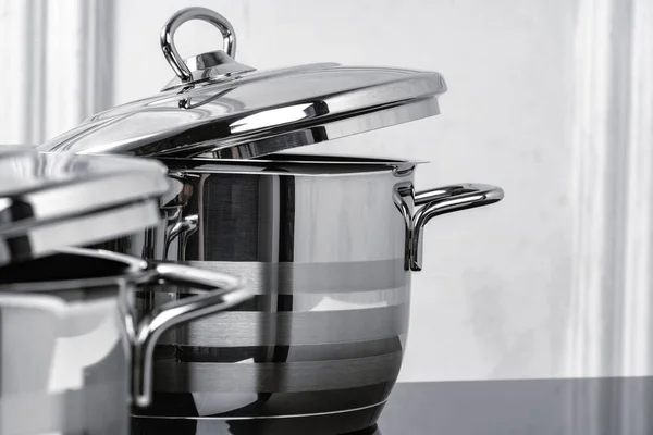 Aluminum cookware on black induction stove against grey wall — Stock Photo, Image