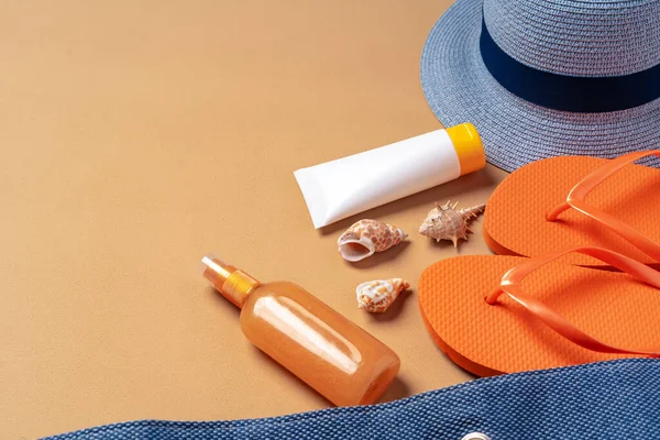 Пляжная сумка с продуктами для загара, шлепанцами и шляпой на бежевом фоне — стоковое фото