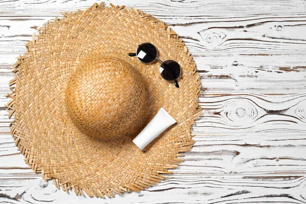 Chapéu de palha, óculos de sol e protetor solar em fundo de madeira — Fotografia de Stock