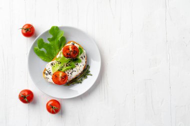 Yumuşak peynirli sandviç ve dilimlenmiş domates.