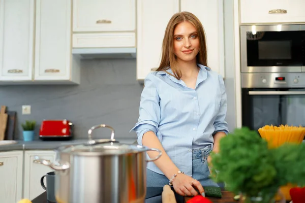 Mulher jovem que corta verduras da salada na cozinha — Fotografia de Stock