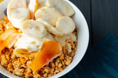 Bir kase tahıl, yoğurt ve dilimlenmiş meyve.