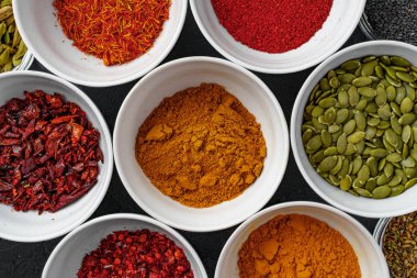 Koyu arkaplanda çeşitli baharatlar bulunan kaseler.