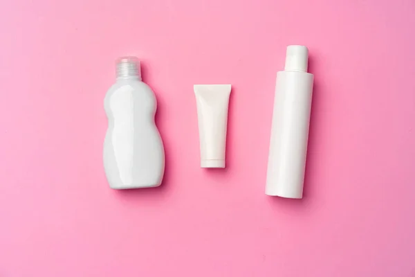 Tres botellas de cosméticos blancos sobre fondo rosa plano laico — Foto de Stock