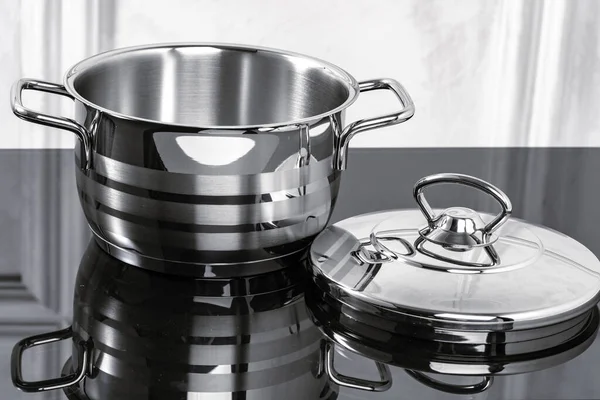 Aluminum cookware on black induction stove against grey wall — Stock Photo, Image