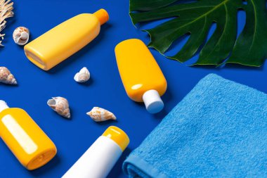 Güneş kremli şişeler ve koyu mavi arka planda deniz kabukları.