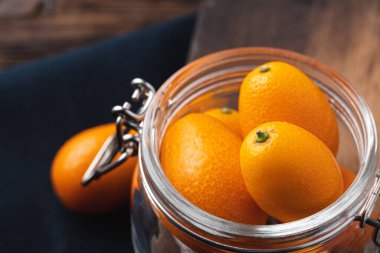 Kumquat citrus meyvesi, koyu ahşap masada.