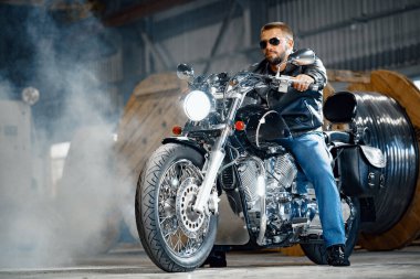 Siyah deri elbiseli motosikletli sakallı bir motosikletli.