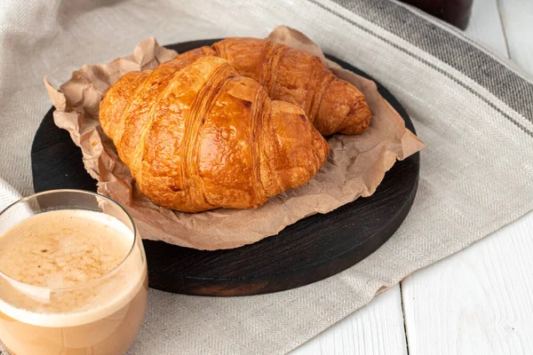 Croissant saboroso com xícara de café com leite na mesa da cozinha — Fotografia de Stock